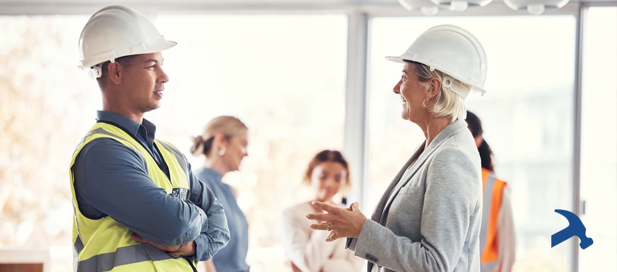 Talking to and vetting a construction contractor - a woman in a hard hat and a man in a hard hat and hi-vis fest talking